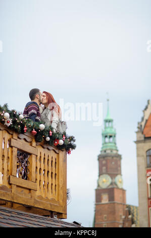 Kurz vor Weihnachten. Junges Paar auf dem Balkon aus Holz dekoriert von einem Urlaub. Romantische Verabredung. Stockfoto