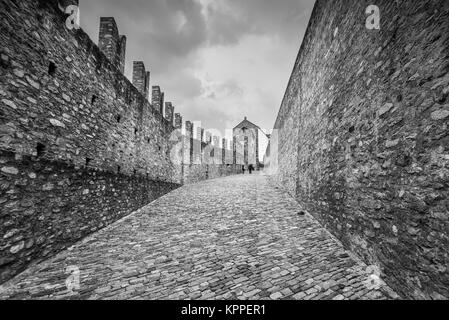 Bellinzona, Schweiz - 28. Mai 2016: Menschen zu Fuß auf den Wänden des Castelgrande Burg in Bellinzona auf die Schweizer Alpen. Schwarz-weiß Foto Stockfoto