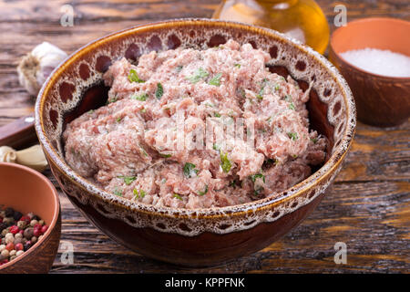 Das Fleisch mit den Gewürzen in einer Schüssel auf einem Holzbrett Schleifen Stockfoto