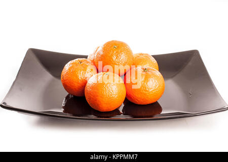 Orangen, Mandarinen, Tangerinen tangerine, auf isolierten weißen studio Hintergrund und schwarzer Platte. Früchte. Stockfoto