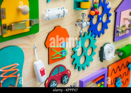 In der Nähe von hellen Besetzt Board für für Kinder. Erziehung der Kinder Spielzeug. Holz- Spielbrett. DIY busyboard. Selektiver Fokus Stockfoto