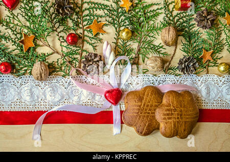 Kekse auf einem roten Band und Spitzenbesatz, Schokolade Herz mit einem Bogen und Zweige von thuja sind auf laubsperrholz Stockfoto