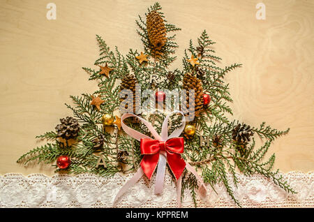 Weihnachtsbaum, aus Zweigen der thuya mit Tannenzapfen und Schokolade Kugeln und Spitze Band auf Holz Sperrholz Stockfoto