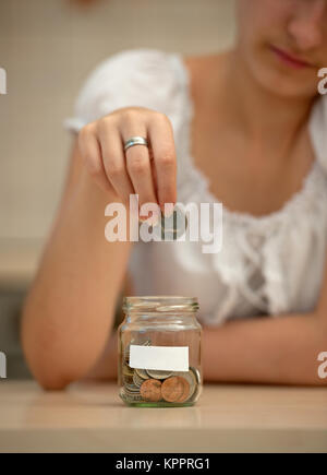 Junge Frau Münze in ein Glas. Fokus auf dem Etikett auf der jar! Das Label bietet Ihnen copyspace für sie Ihren eigenen Text! Stockfoto