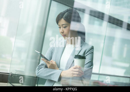 Geschäftsfrau, die Nutzung von Mobiltelefonen im Bürogebäude Stockfoto