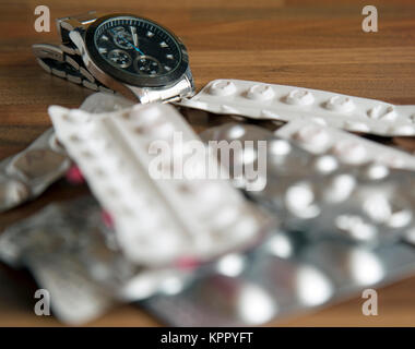 Ein Haufen Teil verwendet verschreibungspflichtige Medikamente auf einer Tischplatte mit eine Uhr im Hintergrund Schuß im Querformat. Stockfoto