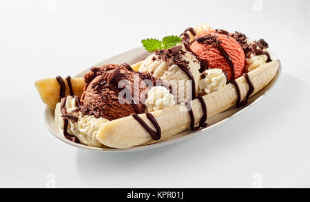 Köstlich süßen Banana Split Eis Dessert mit Pfändung von Schokolade Sirup und Pfefferminzblatt oben in der Schüssel auf dem Tisch Stockfoto