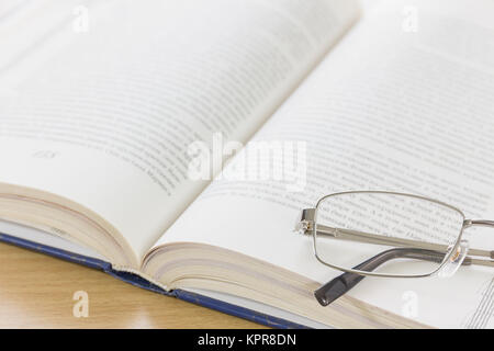 Close up Gläser und offenes Buch auf dem Schreibtisch Stockfoto