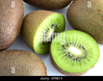 Grüne Kiwi in der Hälfte neben ganzen auf weißem Hintergrund Stockfoto