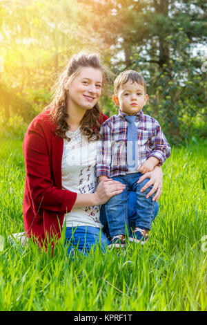 Schöne schwangere Frau mit ihren kleinen Jungen im Freien Stockfoto