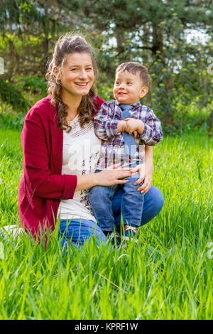 Schöne schwangere Frau mit ihren kleinen Jungen im Freien Stockfoto