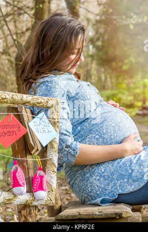 schöne schwangere Frau outdoor im Park auf der Bank Stockfoto