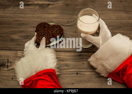 In der Nähe von Santa's Händen herauf Kekse und Milch, die Links in der Tabelle am Heiligabend Stockfoto