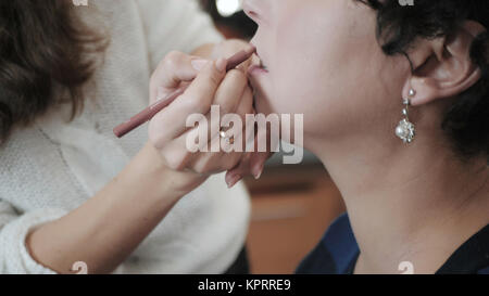 Der Master in Make-up bereitet Modell für historischen Blick. Das Mädchen gilt mit Bleistift Lippenstift für Lippen auf mittleren Alters, schöne Frau. Die Make-up-ar Stockfoto