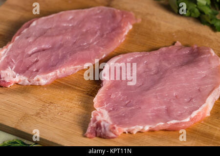 Zwei Stücke von rohem Schweinefleisch geschlagen Schnitzel auf Holz Schneidebrett zu machen Stockfoto