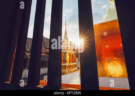 Blick aus dem Fenster der buddhistische Phra Singh Tempel auf den Sonnenuntergang. Touristen bevorzugten Sehenswürdigkeiten in der Innenstadt von Chiang Mai in Thailand. Stockfoto