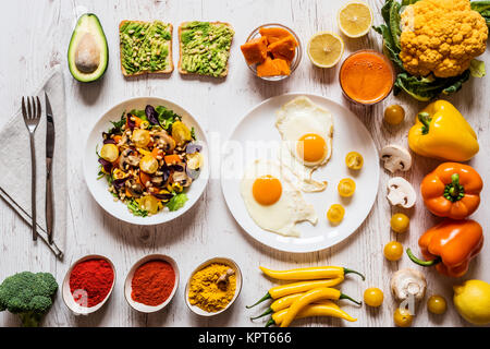 Gesunde Lebensmittel für Frühstück. Spiegeleier, vegan avocado Sandwiches, Gemüse, Salat, gekochten Kürbis, Karotte frischen Saft und Verschiedenen bunten Bio Gemüse und Gewürze Stockfoto