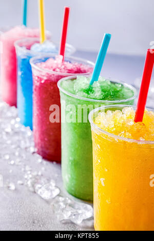 Immer noch Leben der Bunten gefrorenes Obst Granita Slush Drinks in Kunststoff nehmen Sie Tassen mit Trinkhalme geordnet in einer Reihe auf Kaltes Metall Oberfläche durch Eiswürfel Umgeben Stockfoto