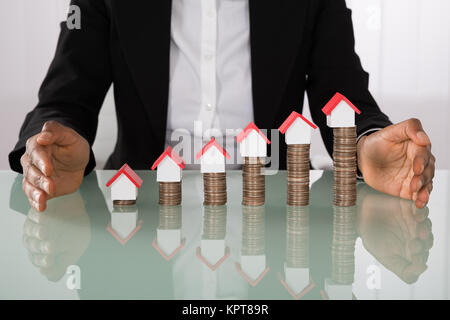 Geschäftsfrau Schutz Haus Modelle auf Gestapelte Münzen Stockfoto