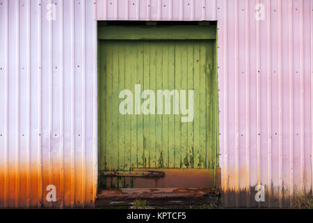 Geschlossene grüne Holztür in Industrial Metal Wall, Hintergrund Textur Stockfoto