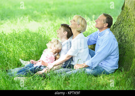 Glückliche Familie entspannen unter Baum Stockfoto