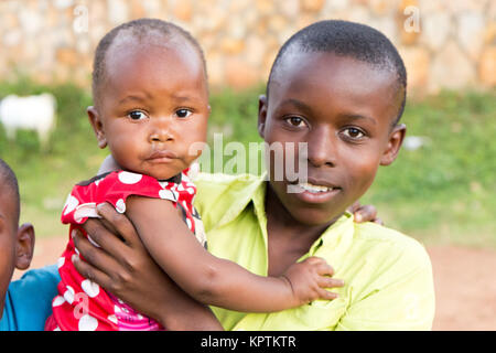 Eine ugandische Boy seine kleine Schwester in die Arme. Stockfoto