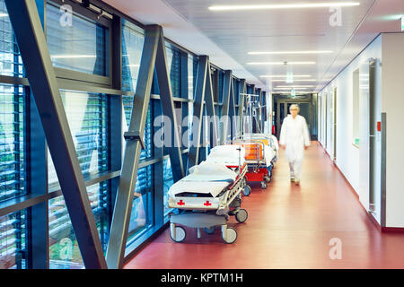 Flur im Krankenhaus mit zwei Betten und geschlossener Tür zur Ambulanz mit Arzt unscharf Stockfoto