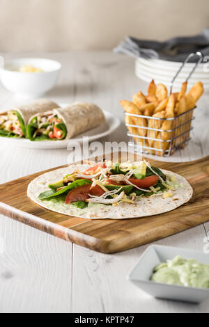 Gegrilltes Hühnerfleisch wraps mit Karotte, Käse, Avocado und Spinat. Mit Pommes Frites auf der Seite. Stockfoto