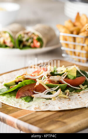 Gegrilltes Hühnerfleisch wraps mit Karotte, Käse, Avocado und Spinat. Mit Pommes Frites auf der Seite. Stockfoto