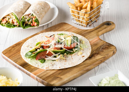 Gegrilltes Hühnerfleisch wraps mit Karotte, Käse, Avocado und Spinat. Mit Pommes Frites auf der Seite. Stockfoto