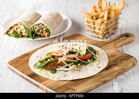 Gegrilltes Hühnerfleisch wraps mit Karotte, Käse, Avocado und Spinat. Mit Pommes Frites auf der Seite. Stockfoto