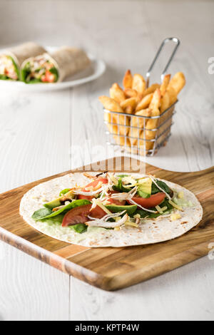 Gegrilltes Hühnerfleisch wraps mit Karotte, Käse, Avocado und Spinat. Mit Pommes Frites auf der Seite. Stockfoto