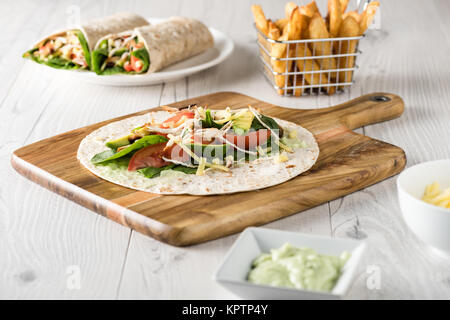 Gegrilltes Hühnerfleisch wraps mit Karotte, Käse, Avocado und Spinat. Mit Pommes Frites auf der Seite. Stockfoto