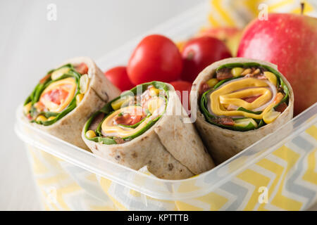 Schinken und Käse hüllt in Lunch-Box mit Apfel und Tomaten Stockfoto