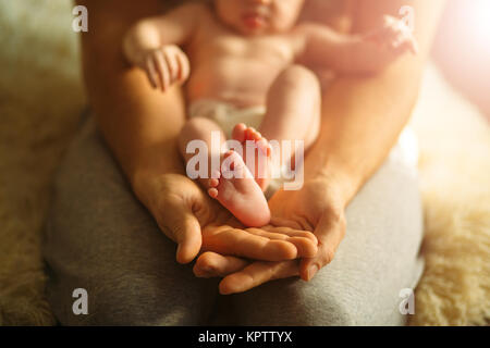 Mutter des neugeborenen Babys Füße. Kleine Füße in der Hand der Frau. Stockfoto