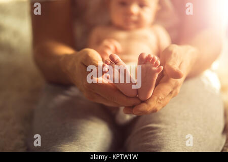 Mutter des neugeborenen Babys Füße. Kleine Füße in der Hand der Frau. Stockfoto