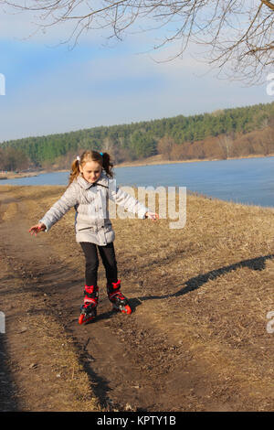 Junge Mädchen geht in Rollschuhen auf dem Boden Stockfoto