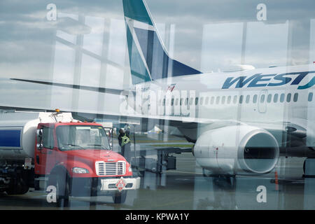 Künstlerische Foto von Kraftstoff tanker Anschluss Tanken WestJet Flugzeug vor einem Flug an einem Internationalen Flughafen Victoria, BC, Kanada 2017 Stockfoto
