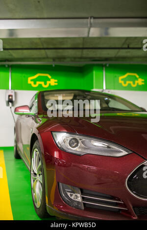 Elektroauto an eine Ladestation in einer Tiefgarage (flacher DOF Farbe getonte Bild) Stockfoto