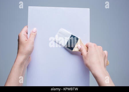Hände halten Malerei Pinsel auf weiße Leinwand Stockfoto