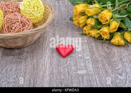 Gelbe Rosen und Herzen auf einem hölzernen Hintergrund Stockfoto