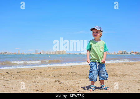 Niedliche kleine Junge stand am Strand Stockfoto