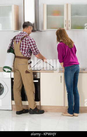 Arbeitnehmer Sprühen von Insektiziden in der Küche Stockfoto