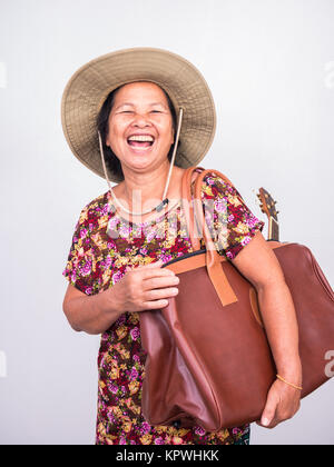 Asiatische bekommt Frau lacht beim Tragen ukulele und Big Brown Bag auf weißem Hintergrund Stockfoto