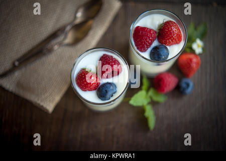 Natürliche Joghurt mit frischen Beeren und Minze auf rustikalem Holz gesunde Dessert oder Frühstück Stockfoto