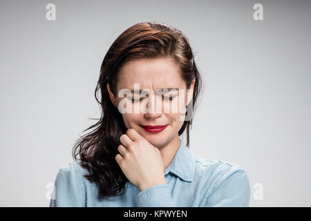 Das Porträt einer weinenden jungen einsame Frau auf grau Stockfoto