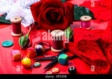 Gewinde, Perle, Schaltfläche und Rose auf leuchtend roten Hintergrund Stockfoto