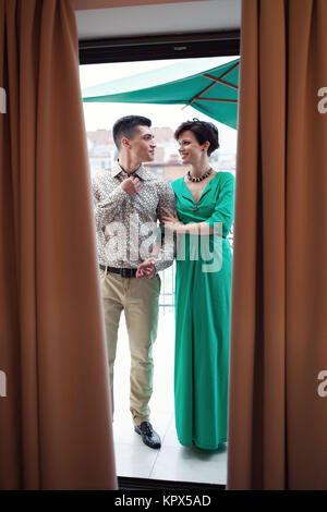 Romantisches date auf dem Balkon. Schönes Paar. Stattliche brünette Kerl mit einem Mädchen in einem grünen Kleid. Stockfoto