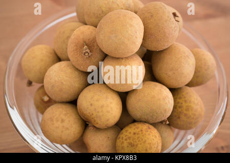 Schüssel gefüllt mit einem Haufen Dimocarpus Longan Früchte auf hölzernen Hintergrund isoliert Stockfoto