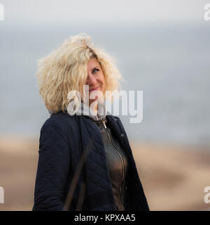 Niedliche lockige blonde Frau mit herrlichem grau-blaue Augen. Stockfoto